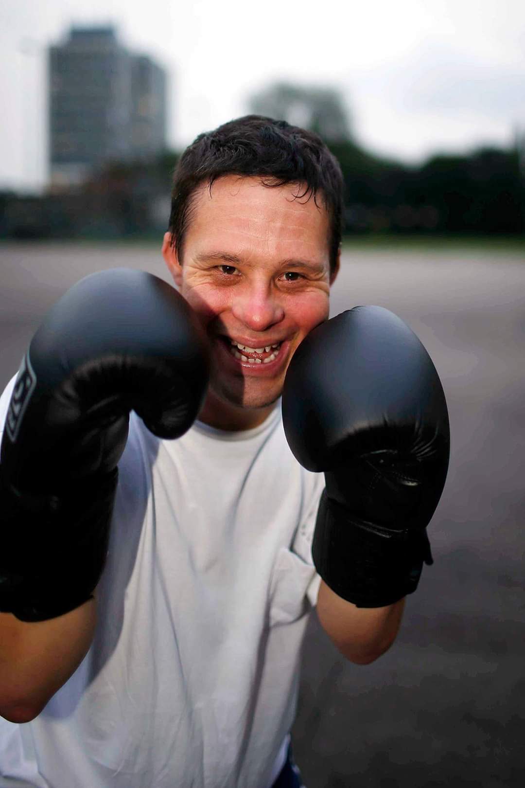 A male boxer with downs syndrome posing with boxing gloves and getting ready for a sparring session.