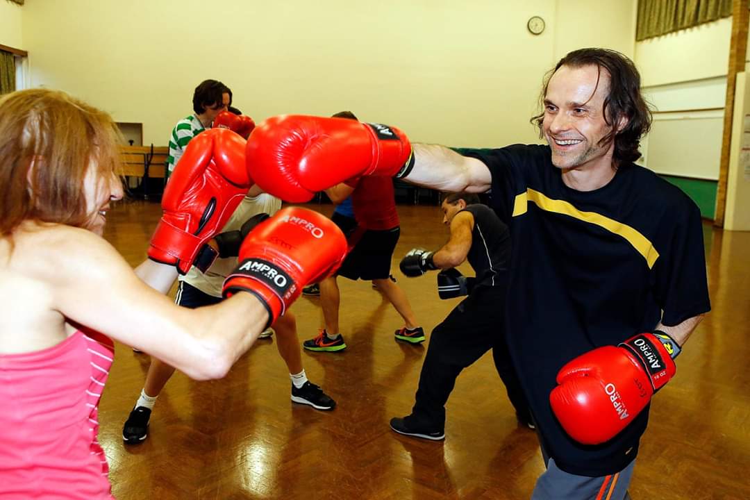 A male boxer sparring with a female boxer and showing that no barriers exist in the sessions.