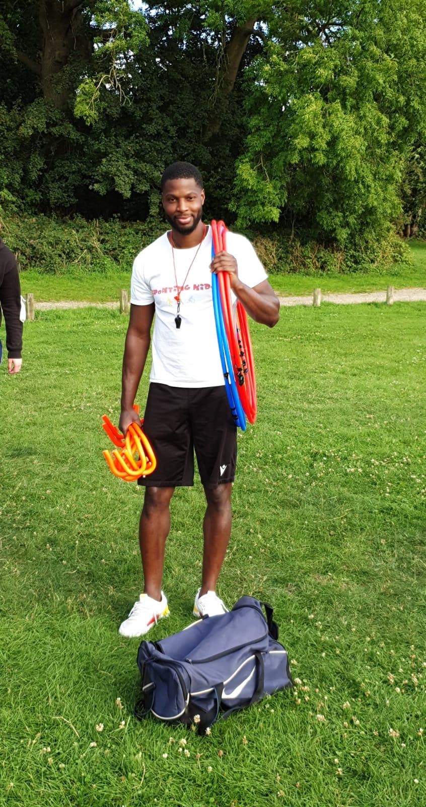 Ola Williams standing with sporting equipment ahead of a Sporting Kids session.