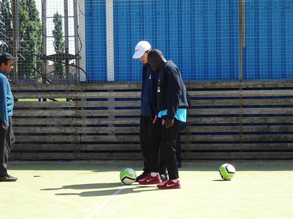 Phoenix Rising Youth Football Club coach Emmanuel Otira talking through ball control with a participant at the Wingate & Finchley Disabled Fans Forum
