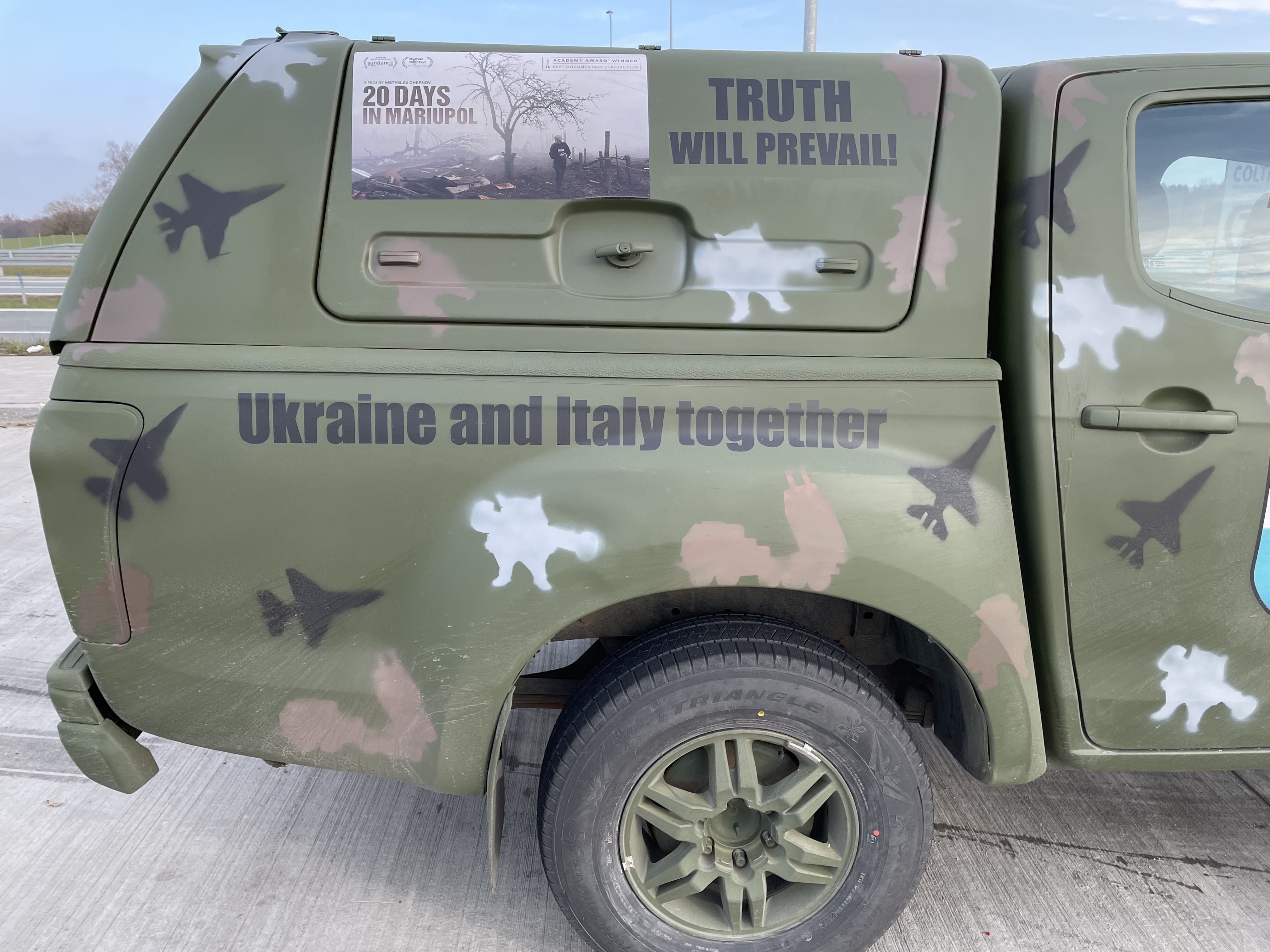 A car painted military green, with "Ukraine and Italy Together" written on the side.
