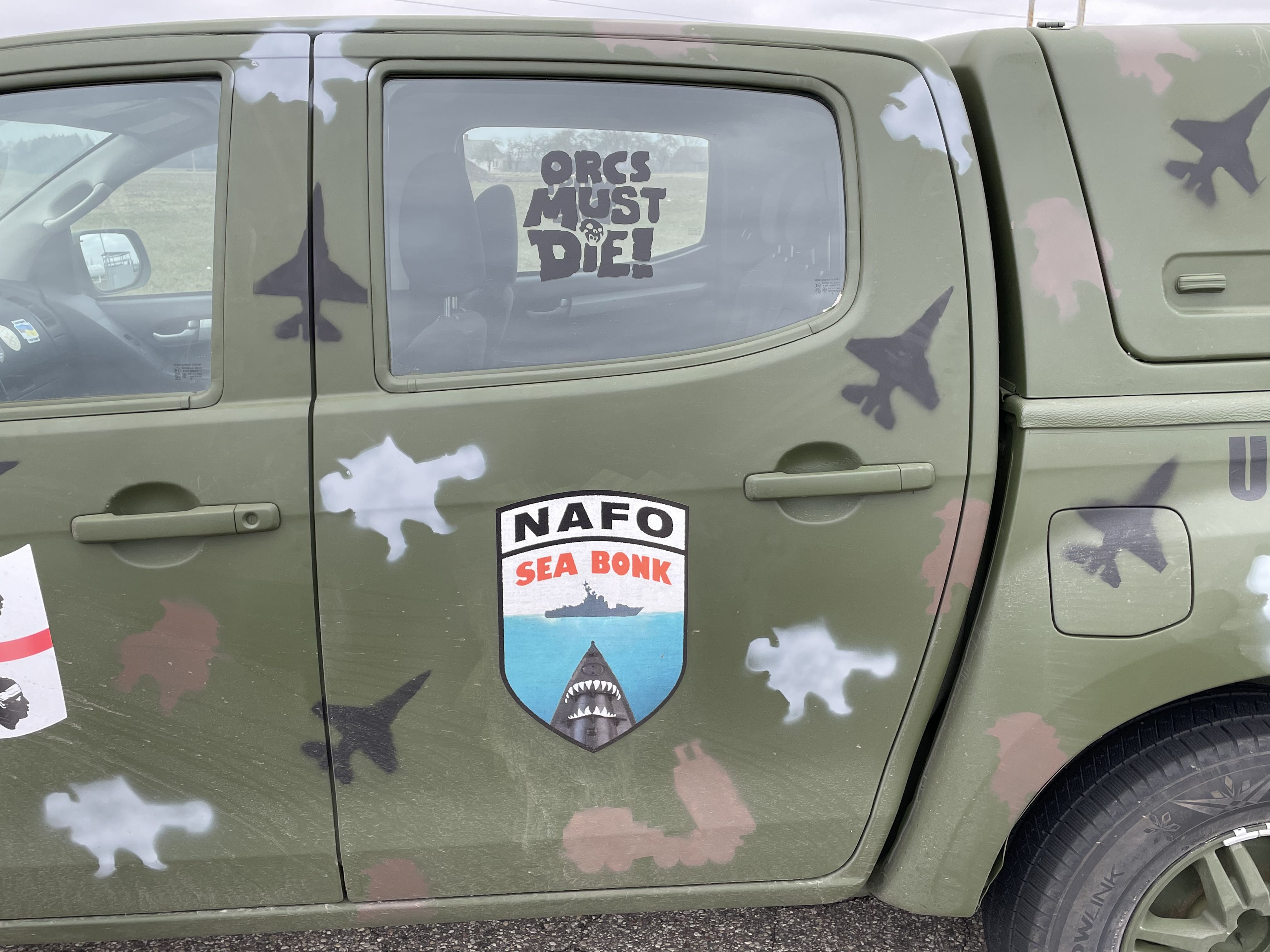 A military green car with "Orcs Must Die!" stencelled on the window.